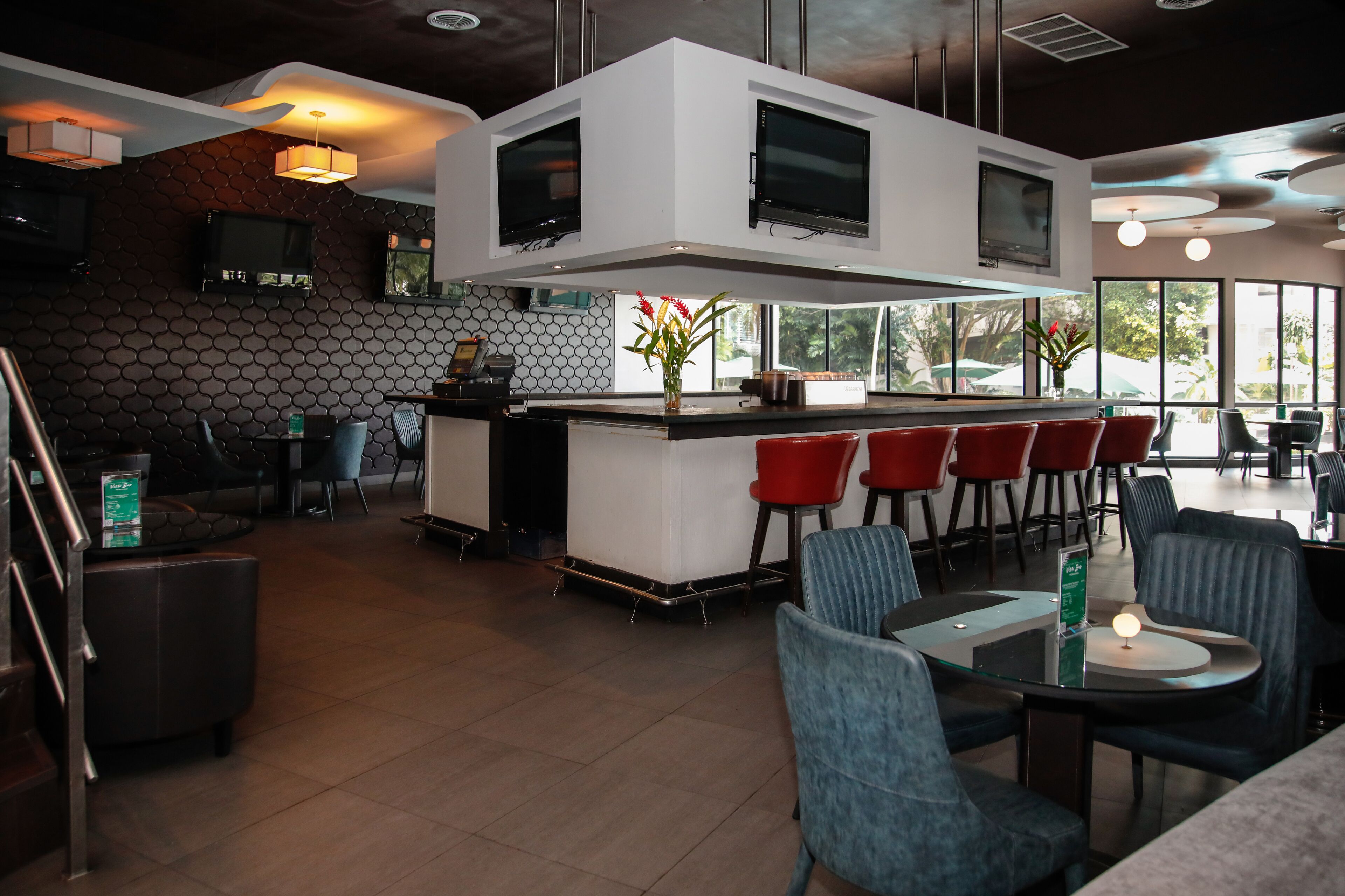 Un restaurante moderno con barra central, zona de estar y amplios ventanales.