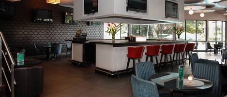 Un restaurante moderno con barra central, zona de estar y amplios ventanales.