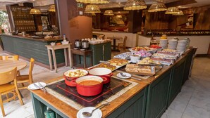 A buffet setup with various food items, a coffee station, and seating arrangements. - H4 La Residence Paulista (São Paulo)