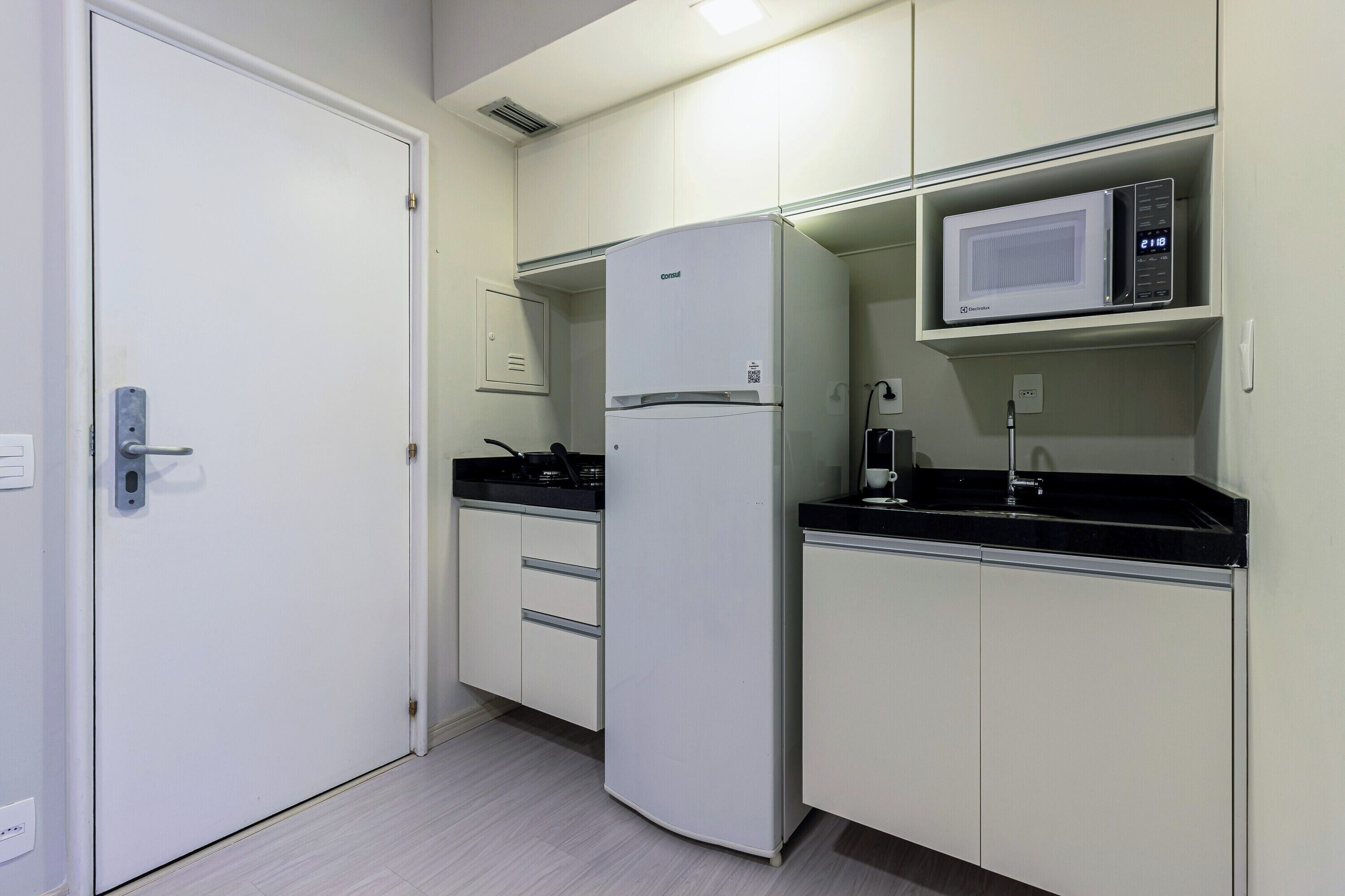 Cocina compacta con refrigerador, microondas y estufa.