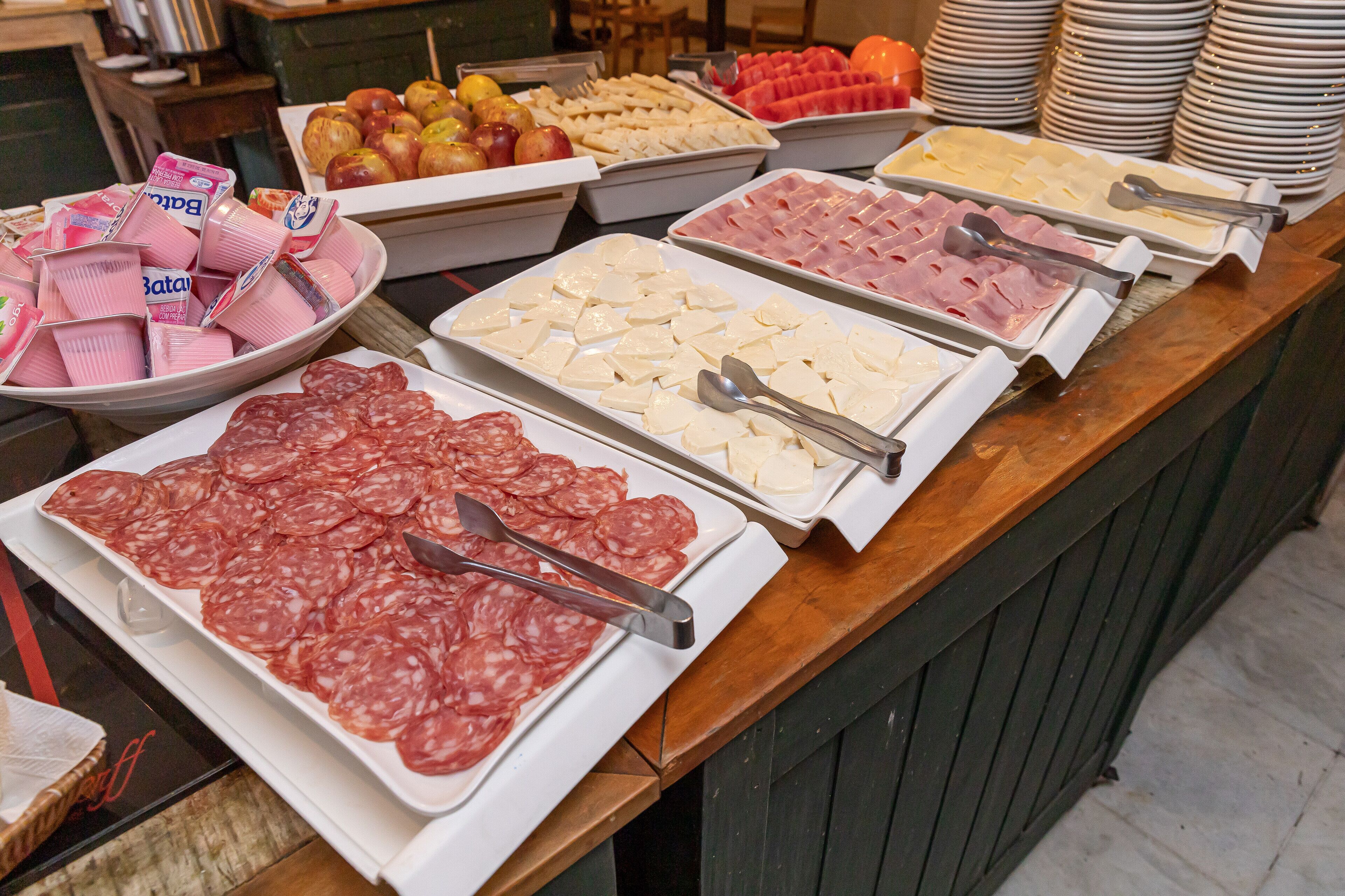 A buffet with various food items including meats, cheeses, and fruits.