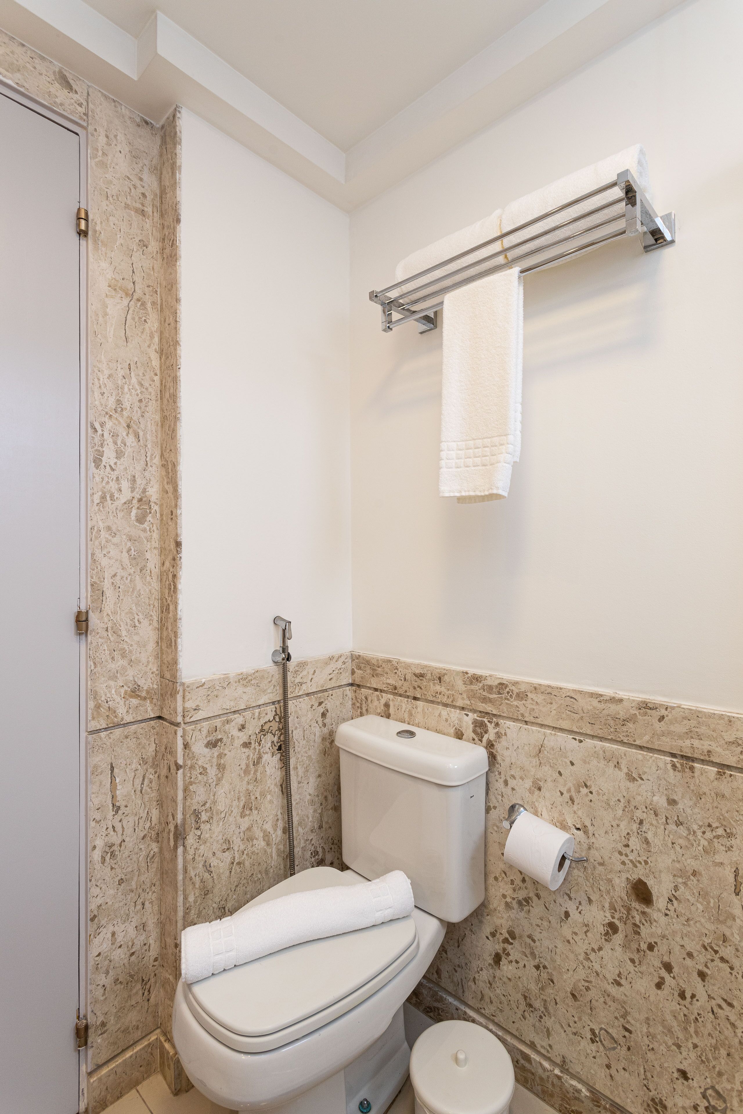 Un baño con inodoro, ducha y un perchero para toallas.