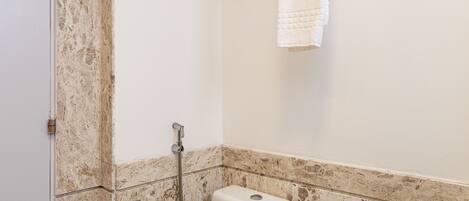 Un baño con inodoro, ducha y un perchero para toallas.