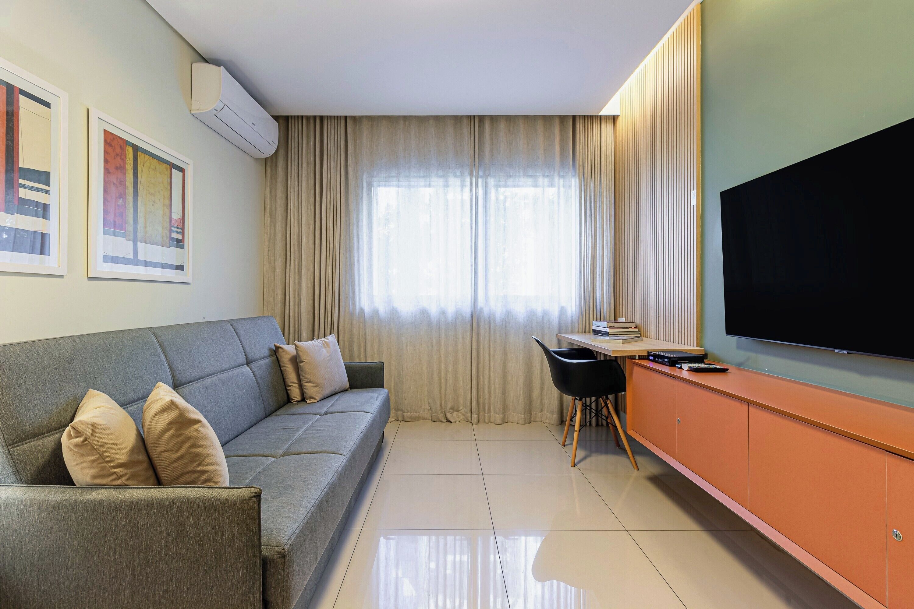 A modern living room with a sofa, a television, a dining area, and a window with curtains.