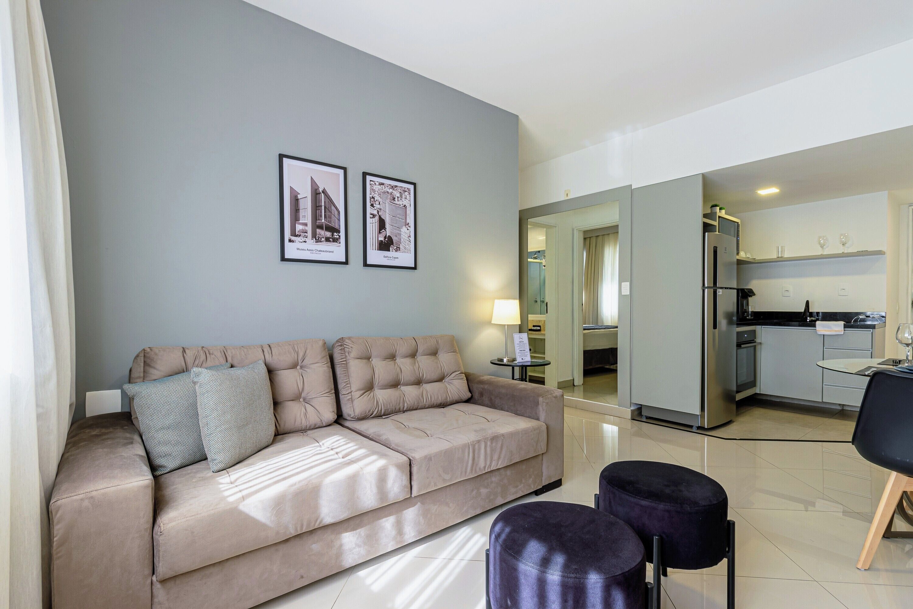 Un salon moderne comprenant un canapé, deux poufs et un coin repas avec une table et des chaises.