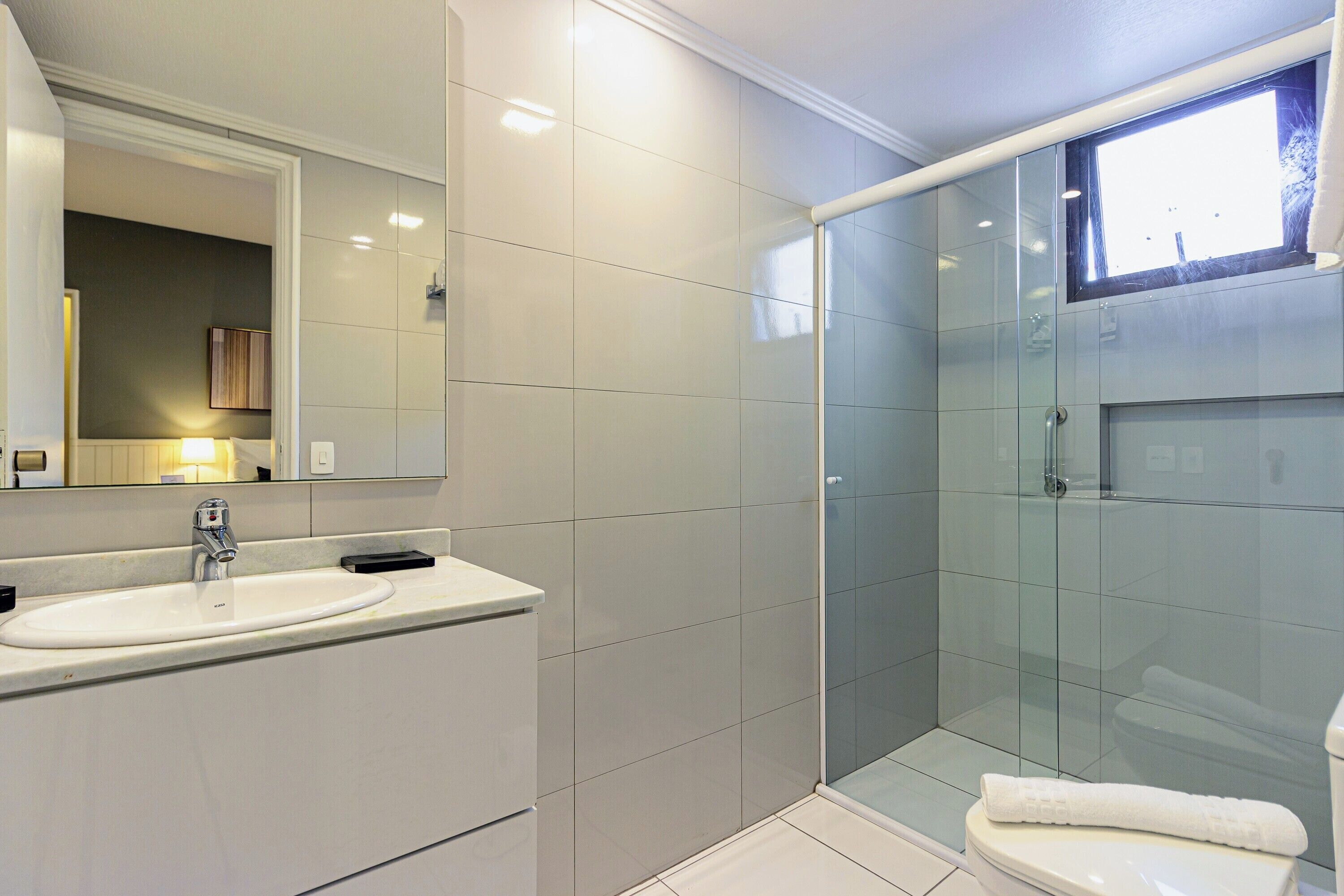 Une salle de bain moderne avec une douche à parois de verre, un lavabo blanc et un miroir au-dessus du lavabo.
