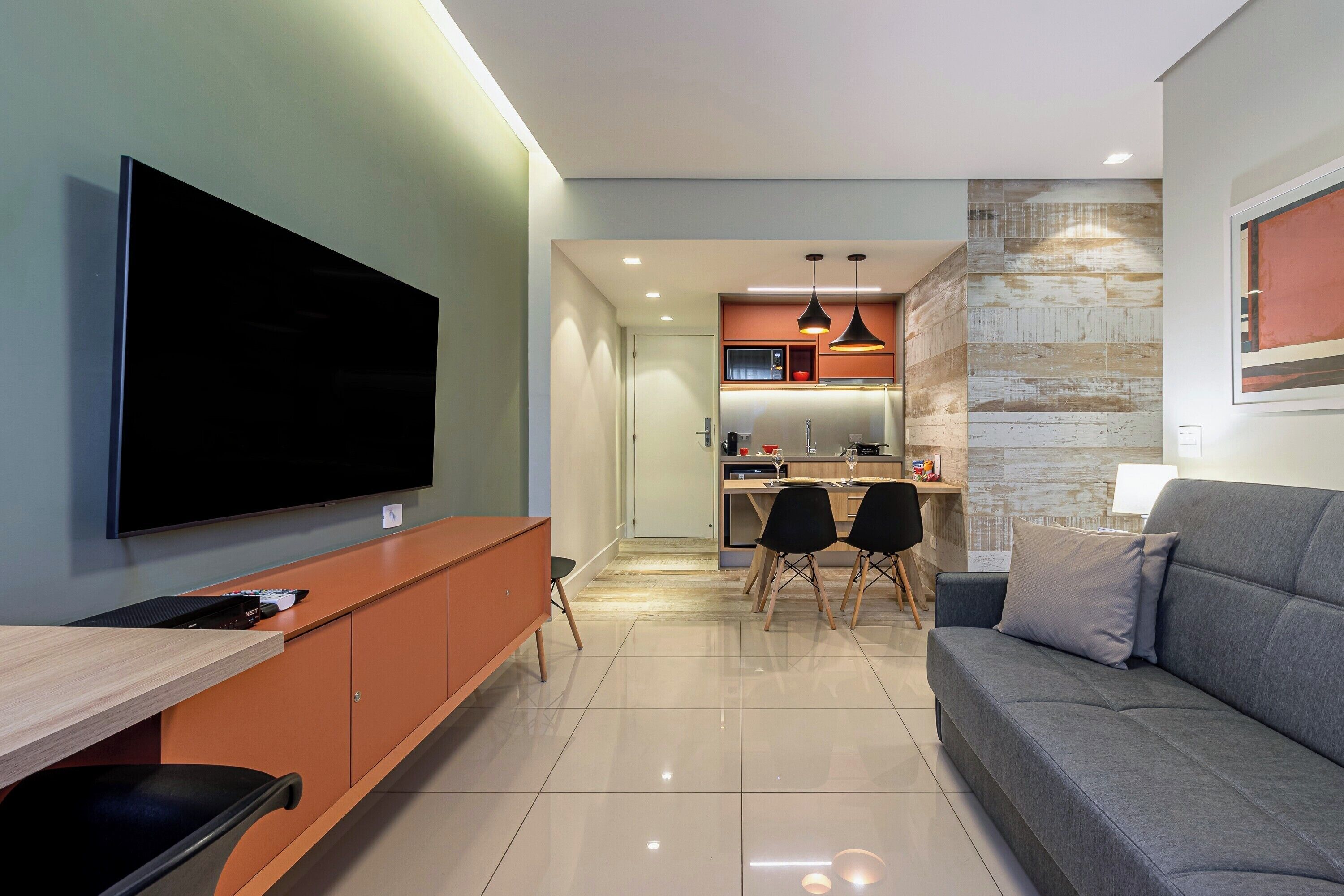 Una sala de estar moderna con televisor de pantalla plana, un sofá y una zona de comedor con sillas.
