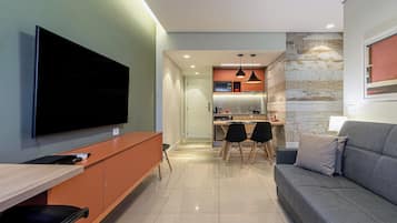 Una sala de estar moderna con televisor de pantalla plana, un sofá y una zona de comedor con sillas.
