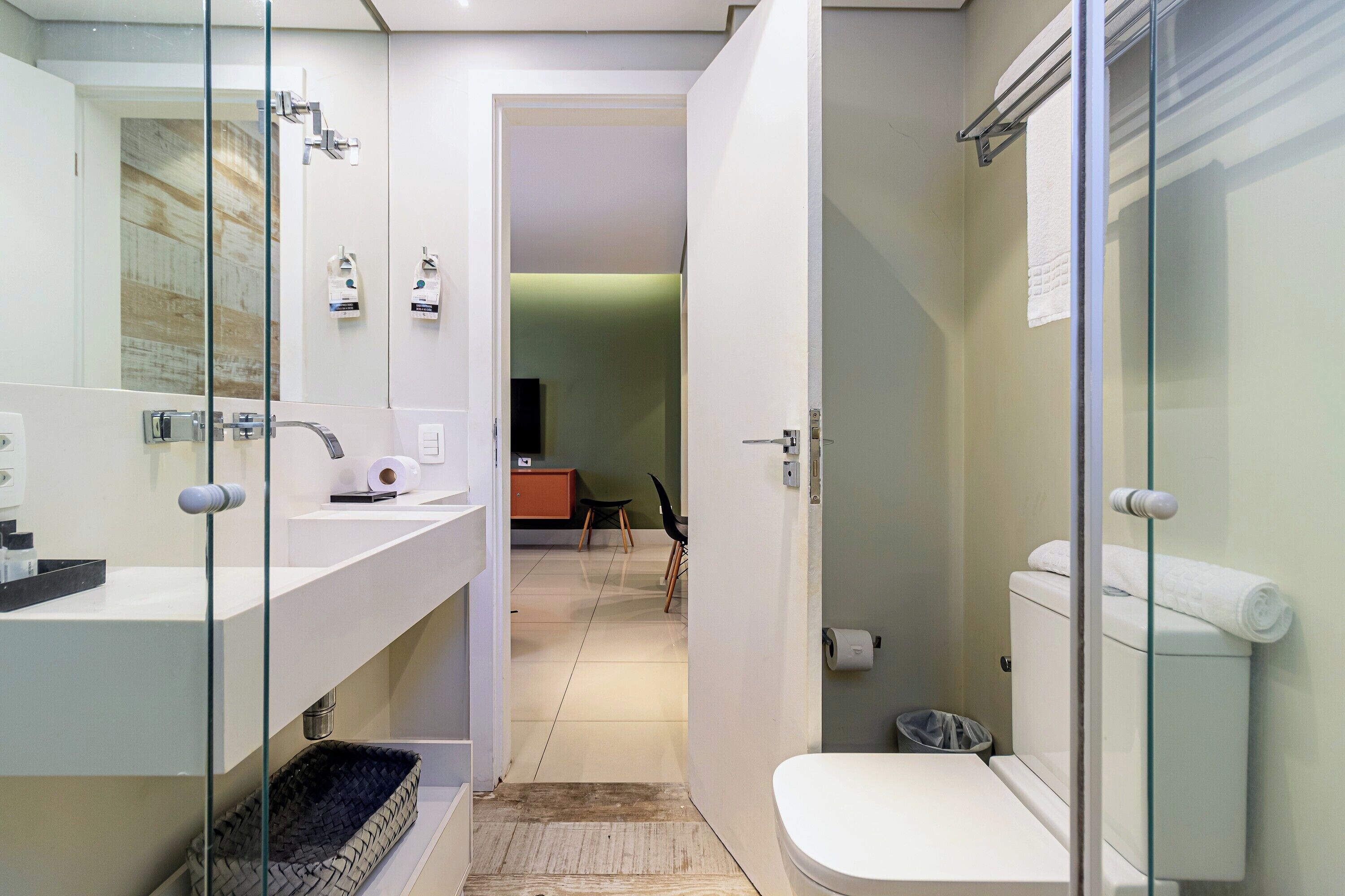 A modern bathroom with a glass shower enclosure, a white toilet, and a sink with a towel rack.