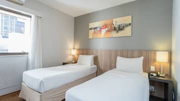 A hotel room with two beds, a cityscape view, and a painting on the wall.