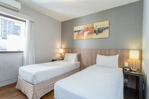 A hotel room with two beds, a cityscape view, and a painting on the wall.