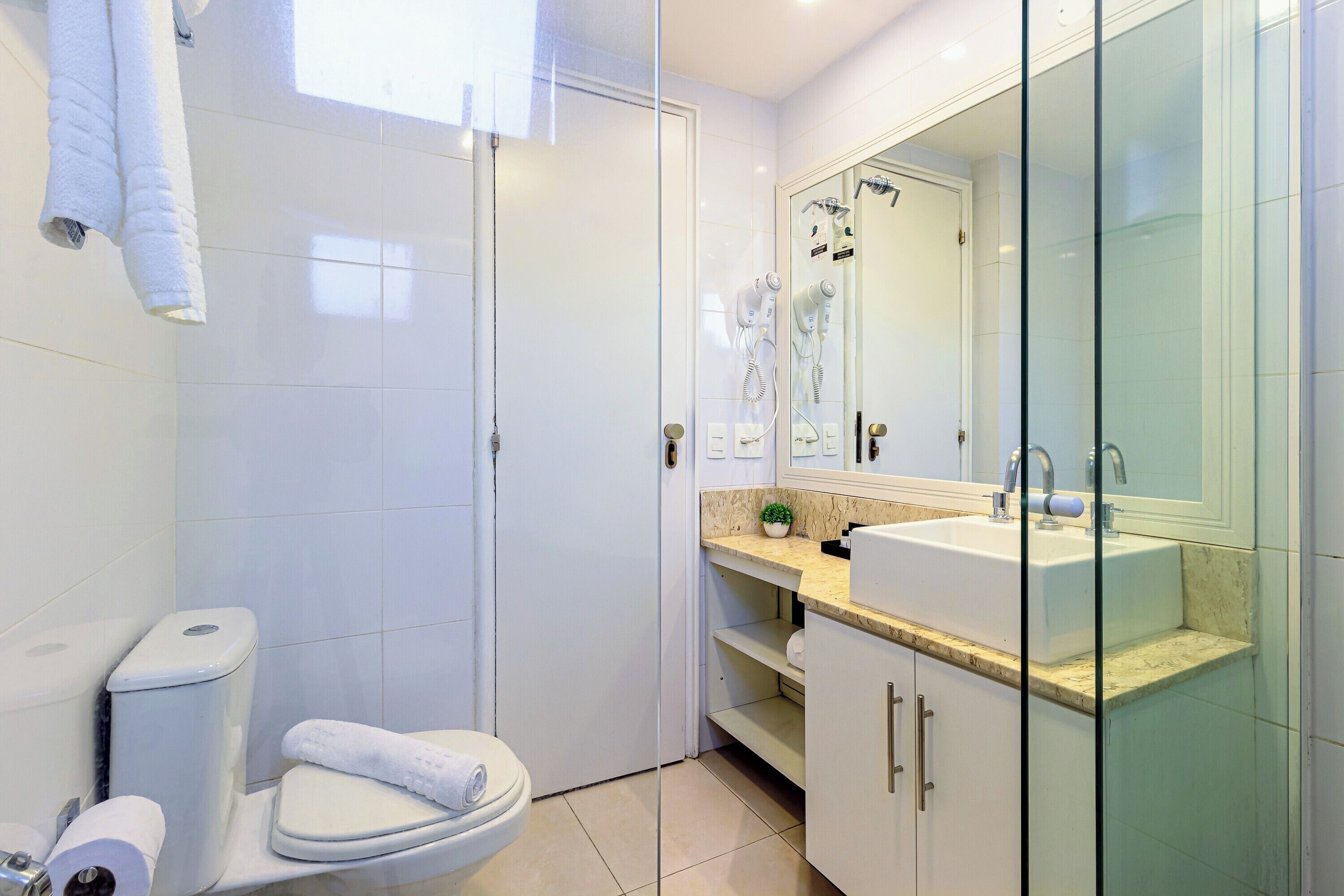 Une salle de bain moderne équipée de toilettes, d’un bidet et d’une douche séparée par une paroi en verre.