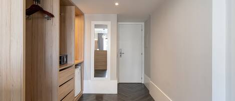 A hallway with wooden cabinets, a microwave, and a door leading to another room.