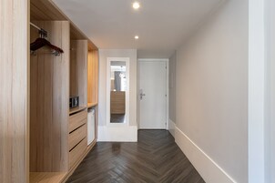 Un pasillo con armarios de madera, un microondas y una puerta que da a otra habitación.