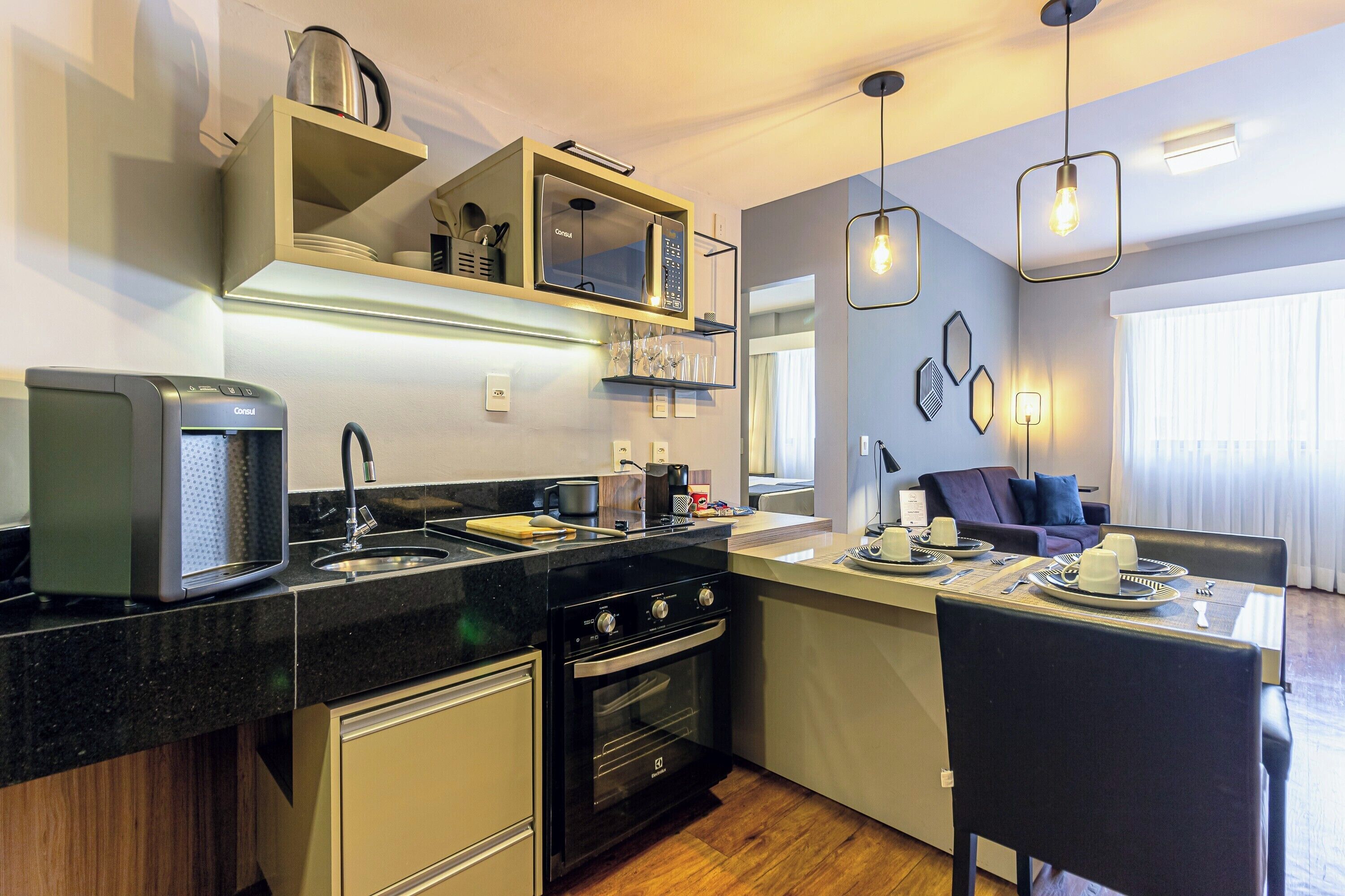 A modern kitchen with a built-in oven, a coffee machine, and a dining area with a table set for two.