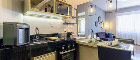A modern kitchen with a built-in oven, a coffee machine, and a dining area with a table set for two.