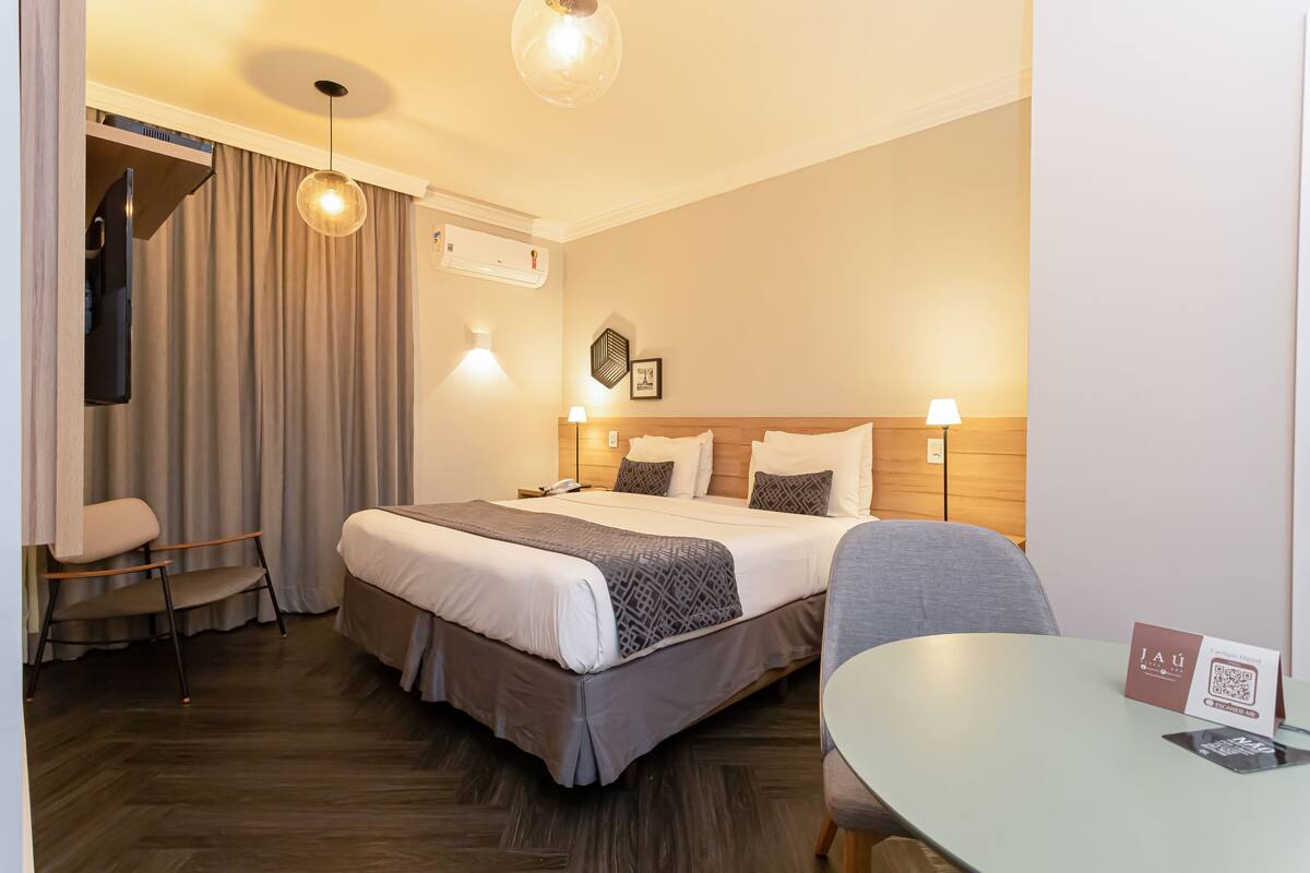 A hotel room with a large bed, bedside lamps, a desk, and a chair.