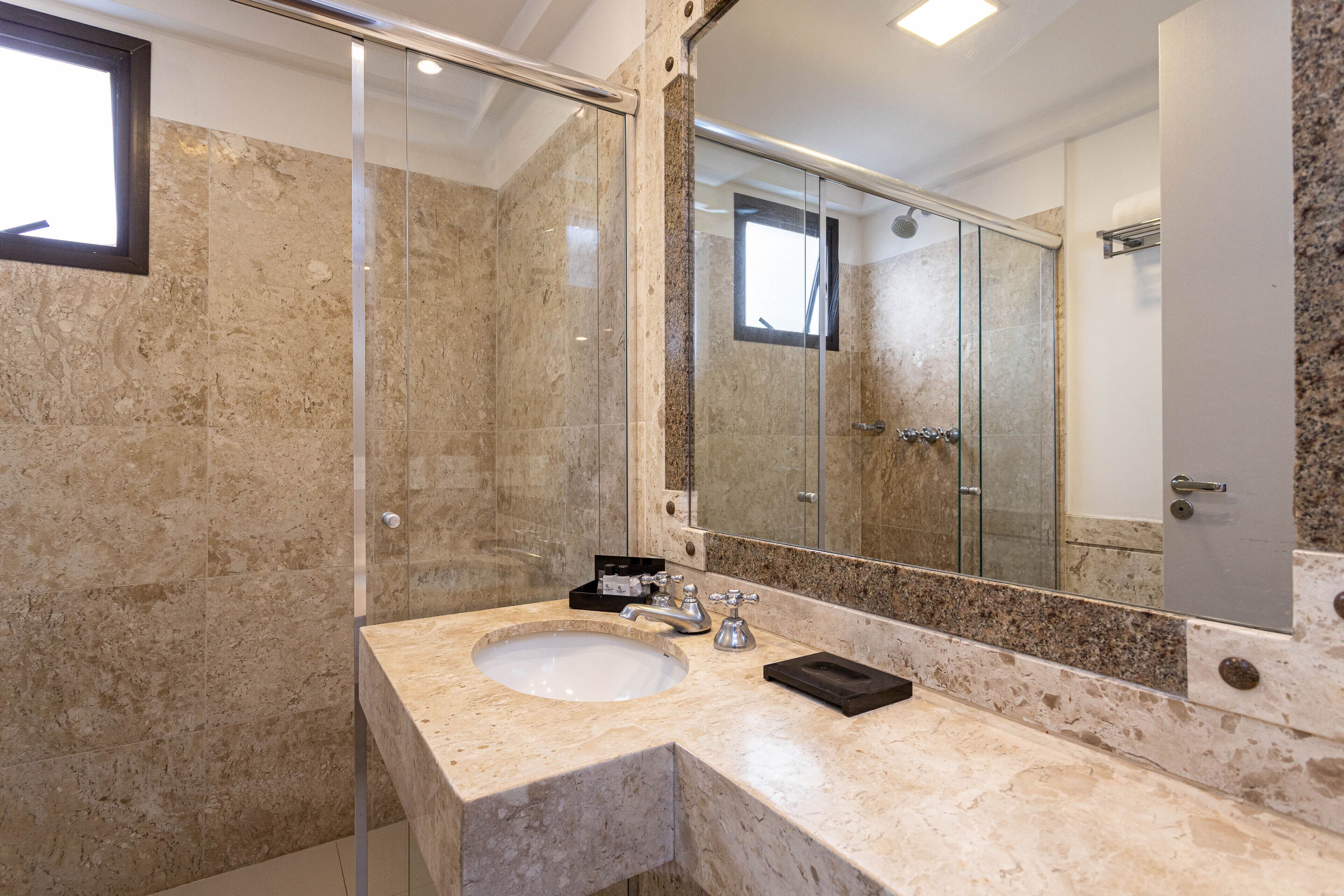 A modern bathroom with a large mirror, a sink, and a shower area.