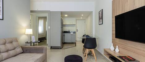 Una sala de estar moderna con un sofá, un televisor y un comedor con mesa y sillas.