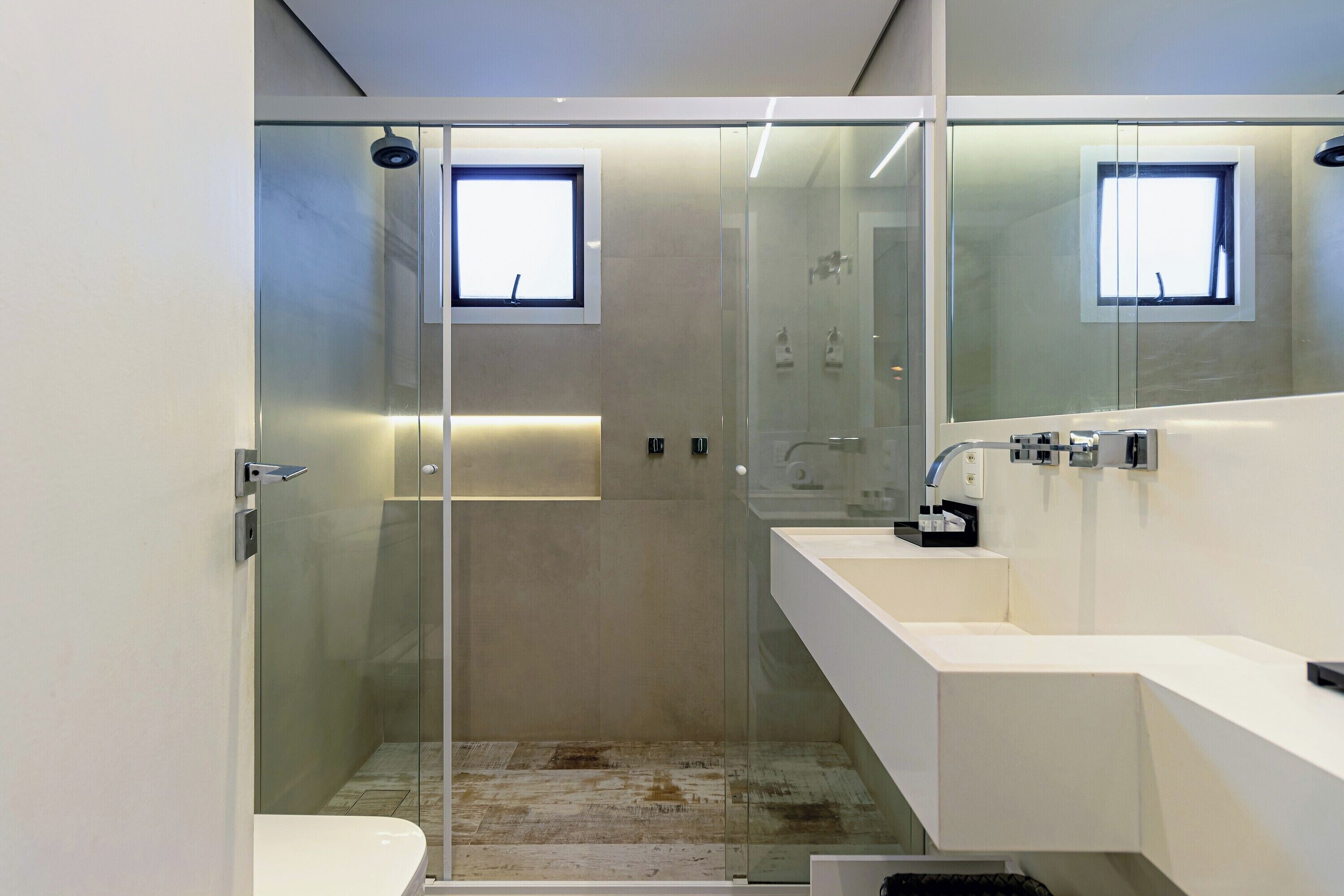 A modern bathroom with a glass-enclosed shower, a white sink, and a mirror.