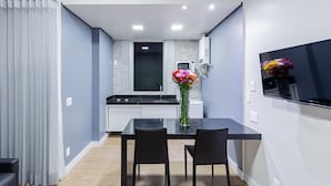 Una cocina moderna con comedor, que incluye una mesa de comedor negra, dos sillas y un florero con flores.