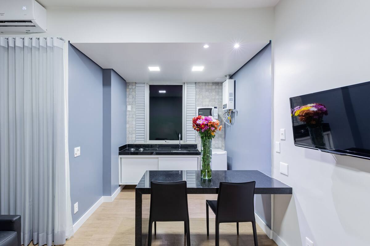 Une cuisine moderne avec un coin repas, comprenant une table à manger noire, deux chaises et un vase avec des fleurs.
