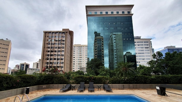 Una piscina con sillas de descanso y vistas a edificios altos al fondo.