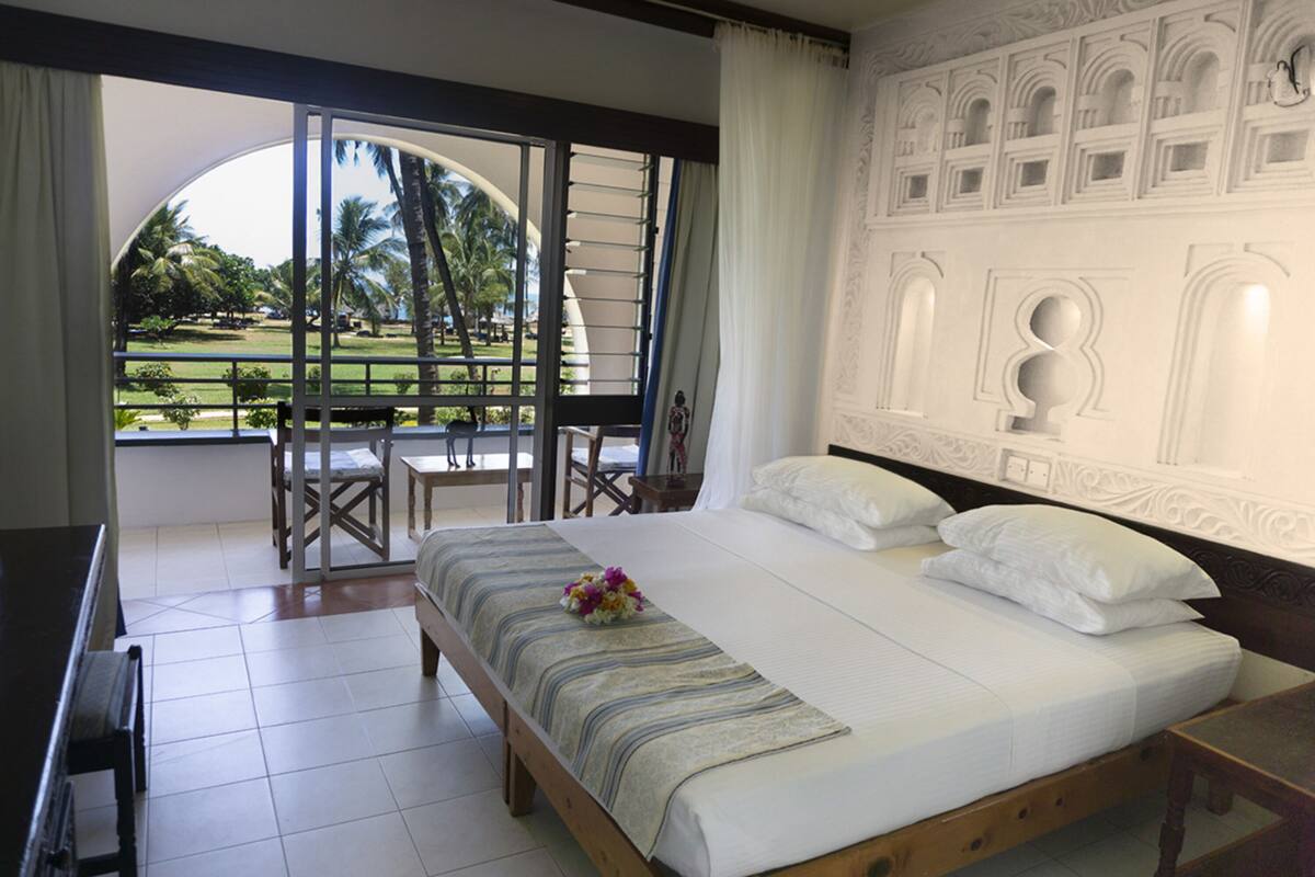 Una habitación de hotel con una cama grande, un balcón con vistas a un campo de golf y una pared decorativa.