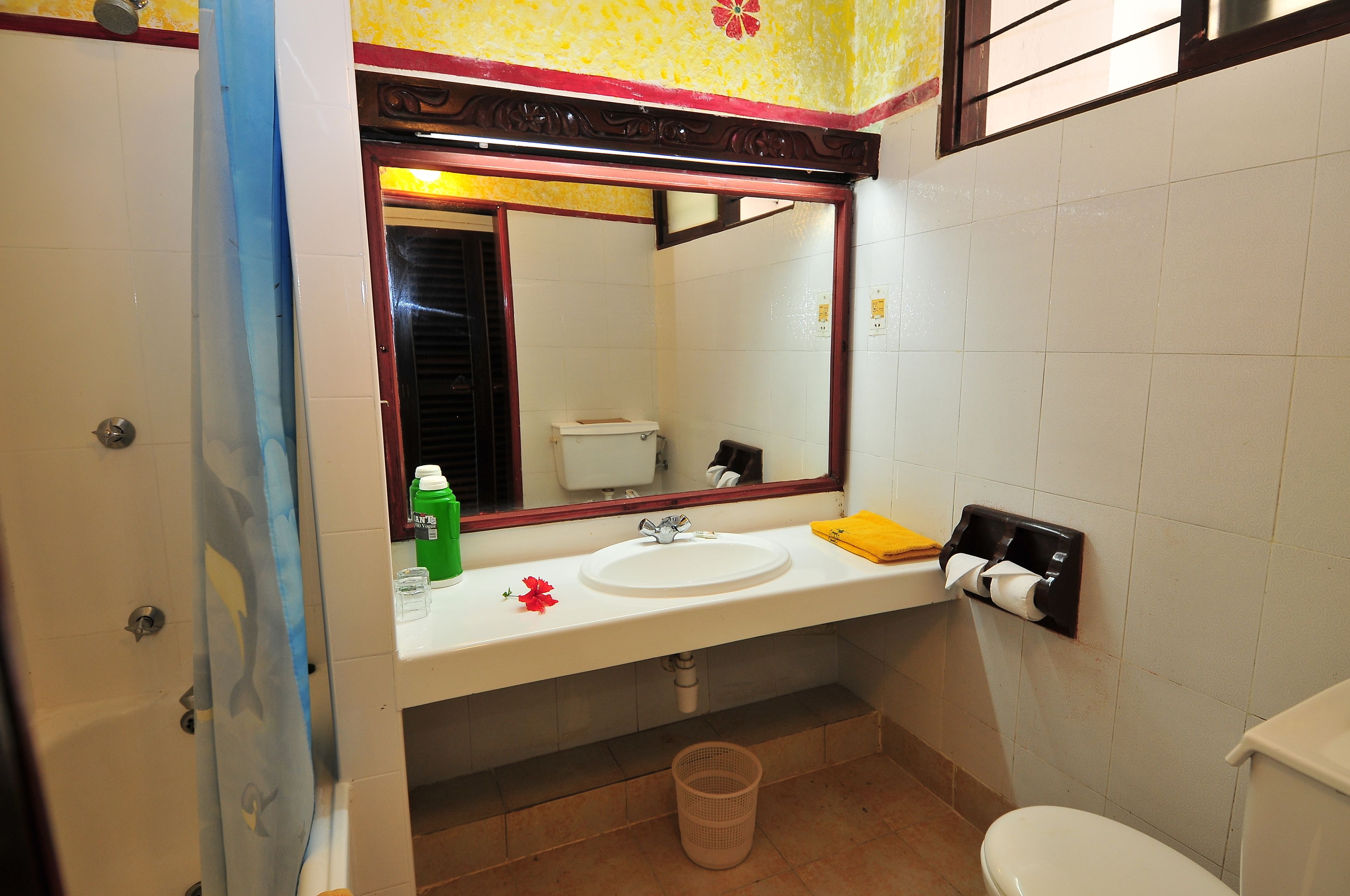 A bathroom with a white sink, mirror, toilet, and shower area.