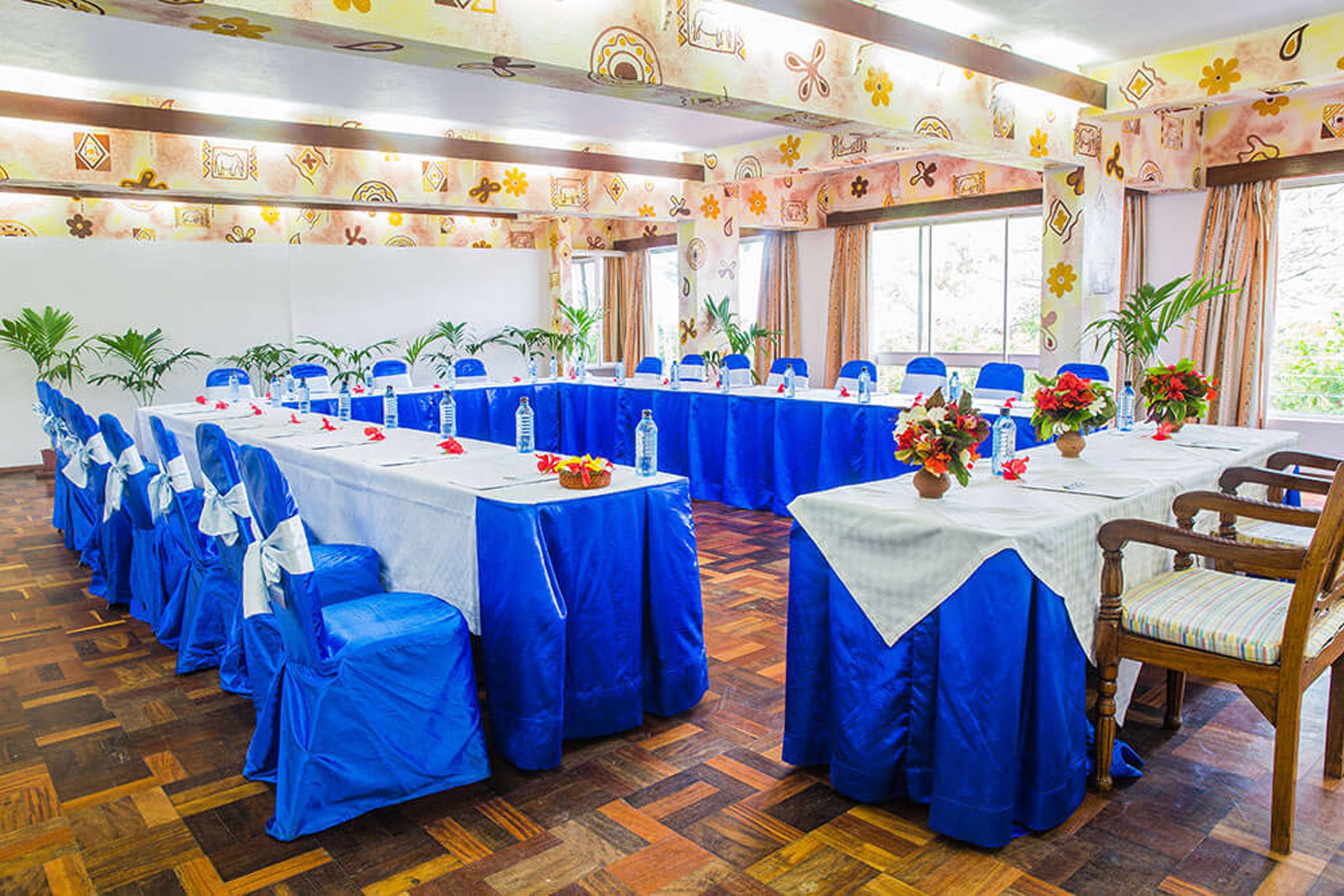 Un salón de conferencias con varias mesas, manteles azules y sillas.