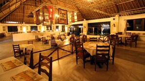 Une salle à manger spacieuse, dotée de hauts plafonds et comprenant plusieurs tables et chaises.