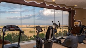 A gym with exercise equipment and a large window overlooking a scenic landscape.