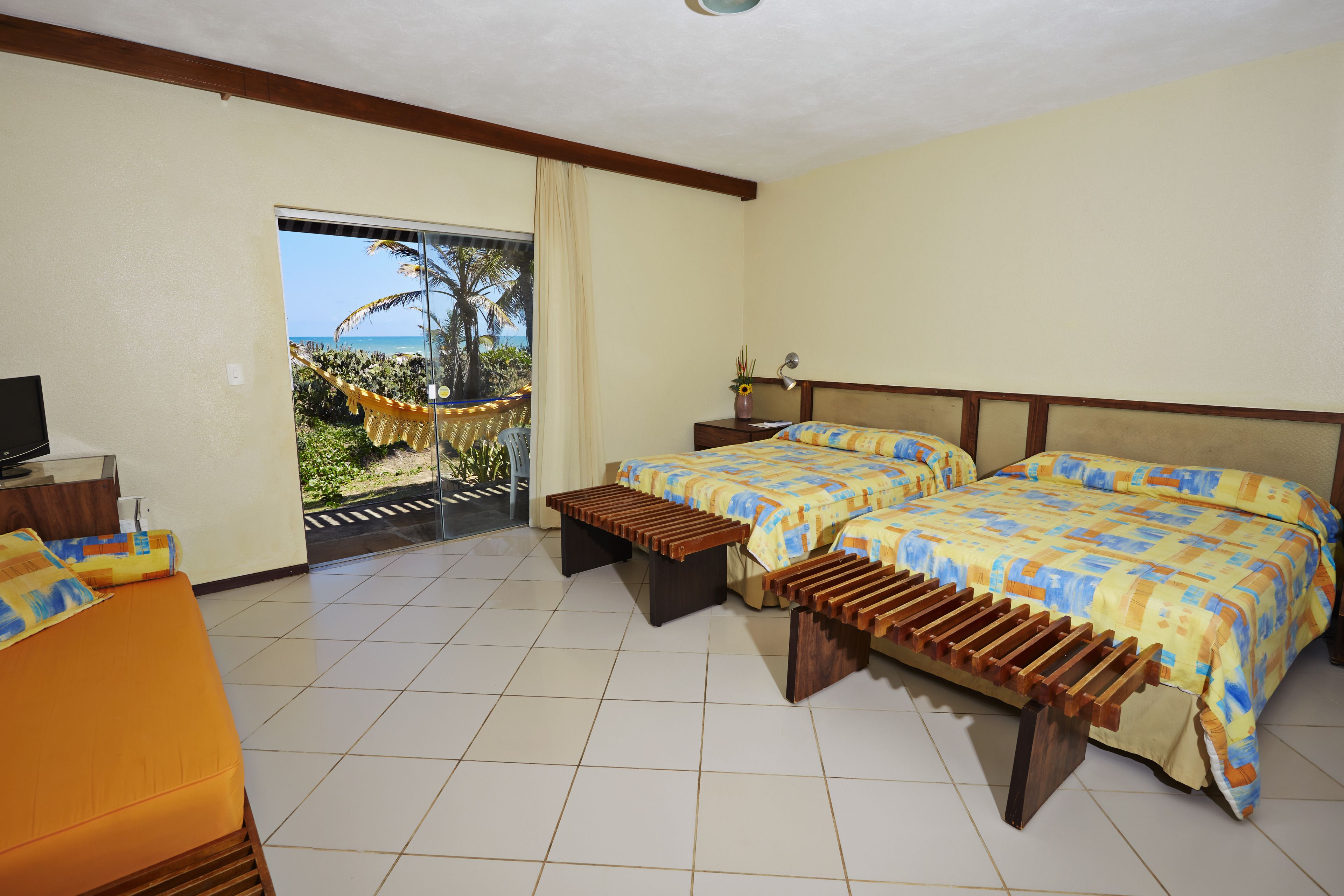 A hotel room with two beds, a sofa, a small table, and a view of the ocean.