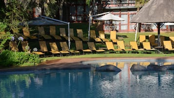 Una piscina al aire libre, sombrillas, sillones reclinables de piscina