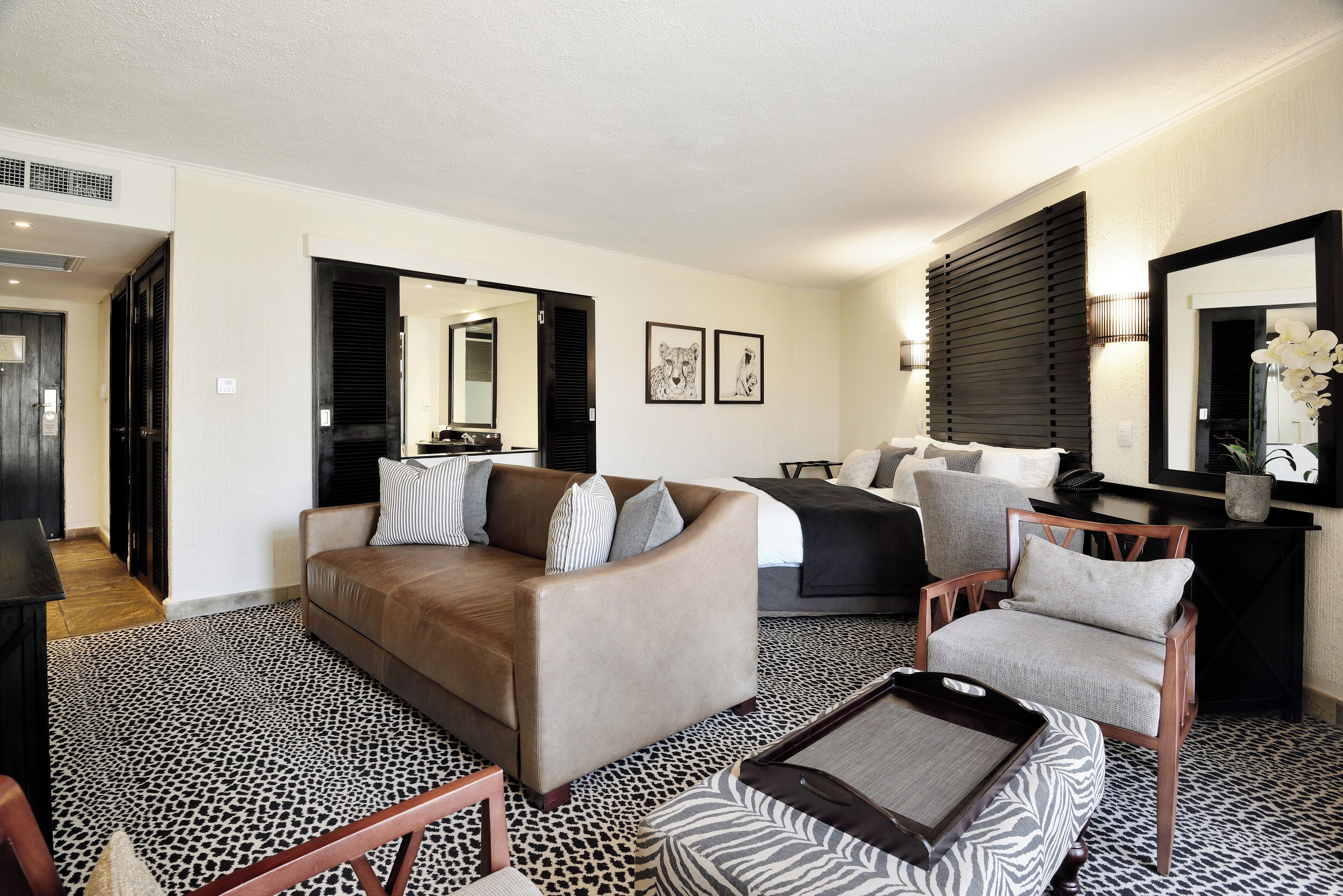 Una sala de estar moderna con un sofá, un sillón y una alfombra estampada.