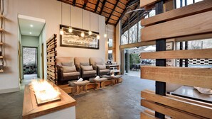 A spacious living area with a large sofa set, wooden benches, and a fireplace. - Bakubung Bush Lodge (Pilanesberg National Park)