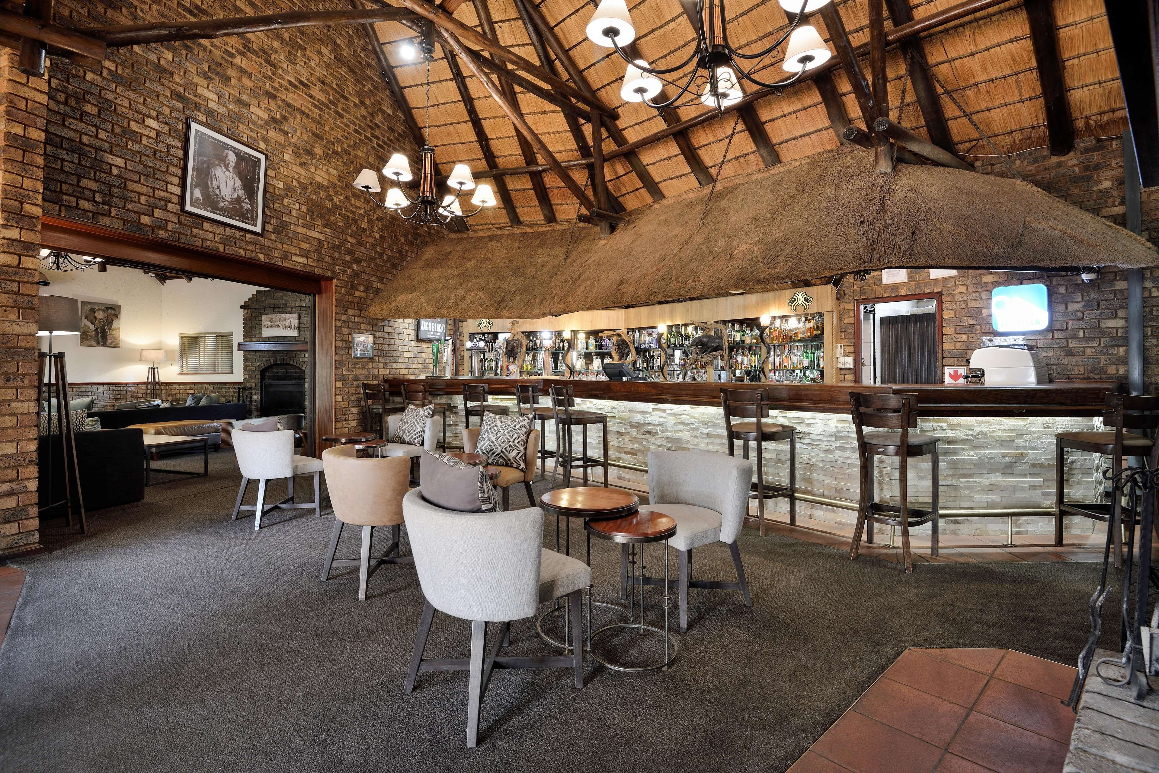 A cozy bar area with brick walls, wooden ceiling beams, and a rustic ambiance.