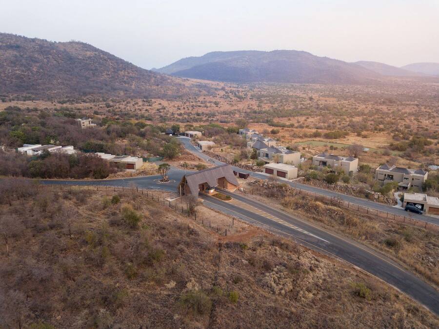 Un quartier résidentiel avec des maisons, une route sinueuse et un paysage vallonné en arrière-plan.