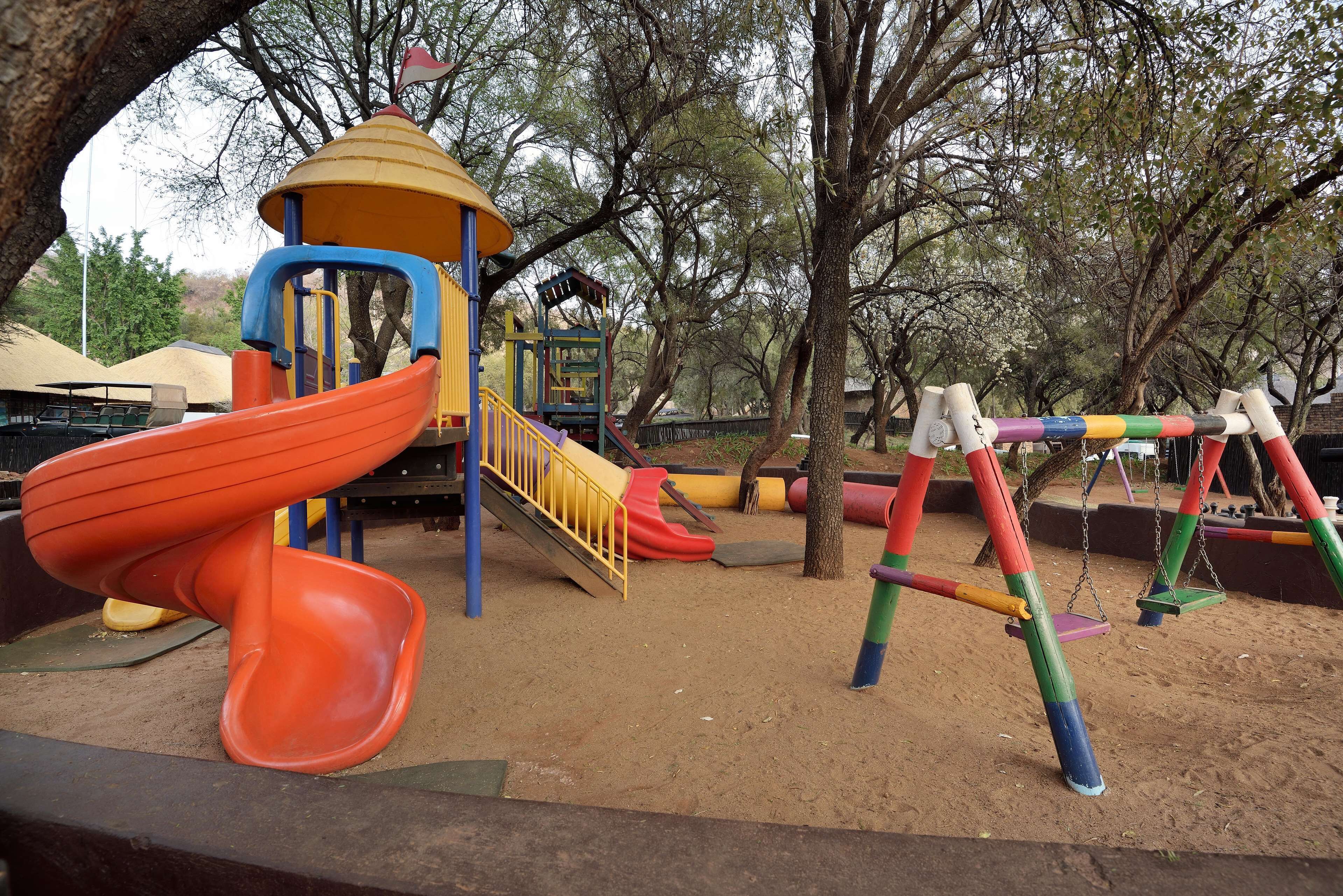 Un parque infantil con tobogán, columpios y estructura para escalar.
