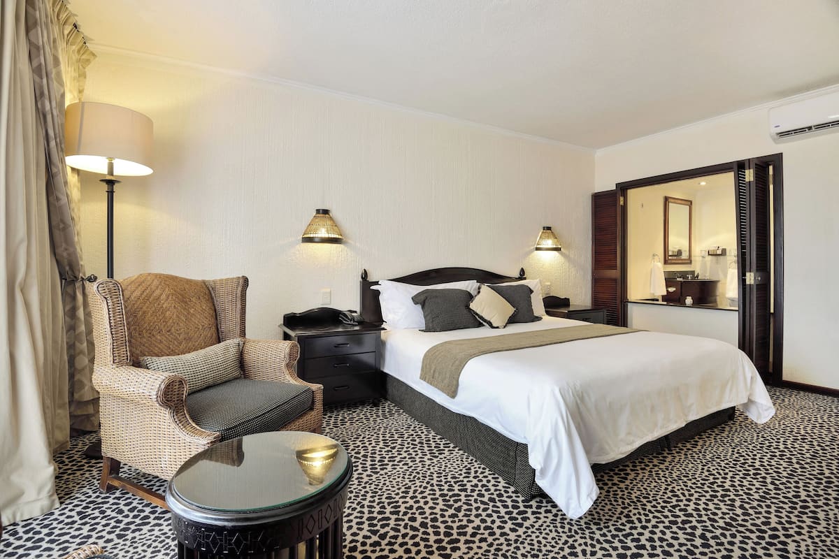 Una habitación de hotel con una cama, una silla, una mesita de noche, una lámpara y una mesa.