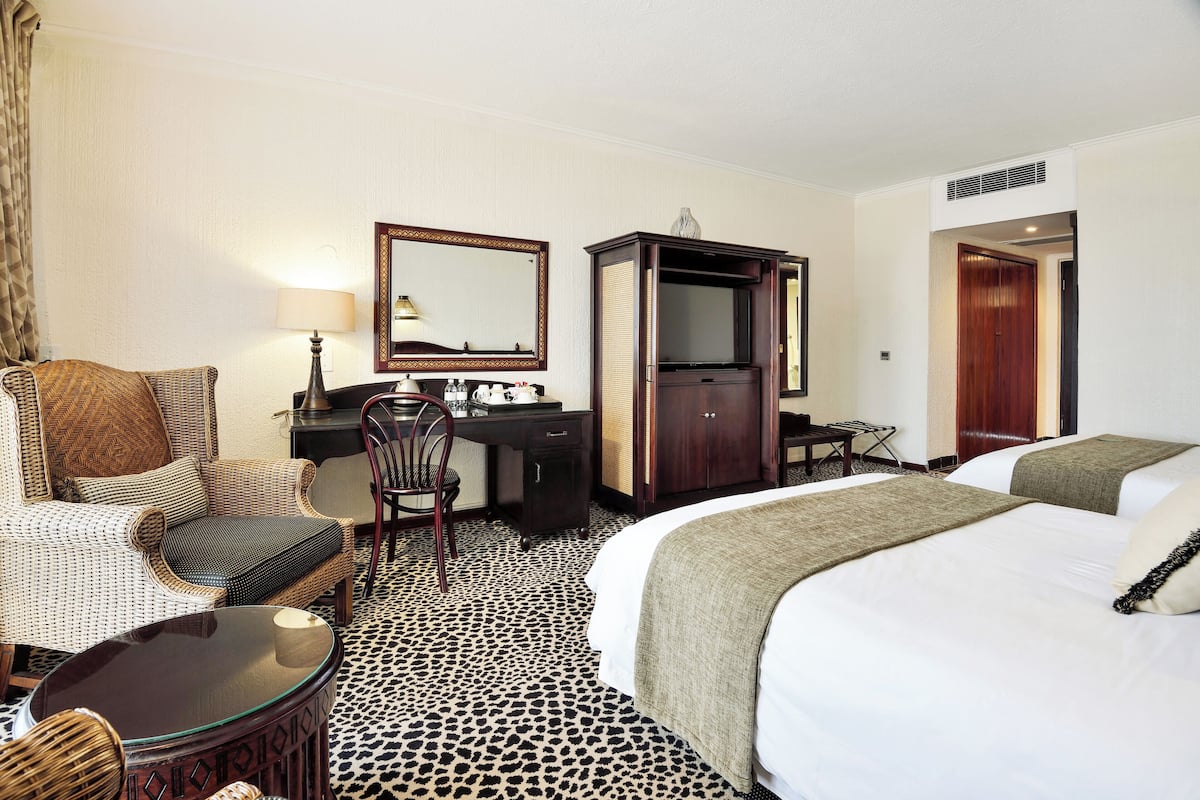 Una habitación de hotel con una cama grande, un escritorio con una silla, un televisor y un armario.