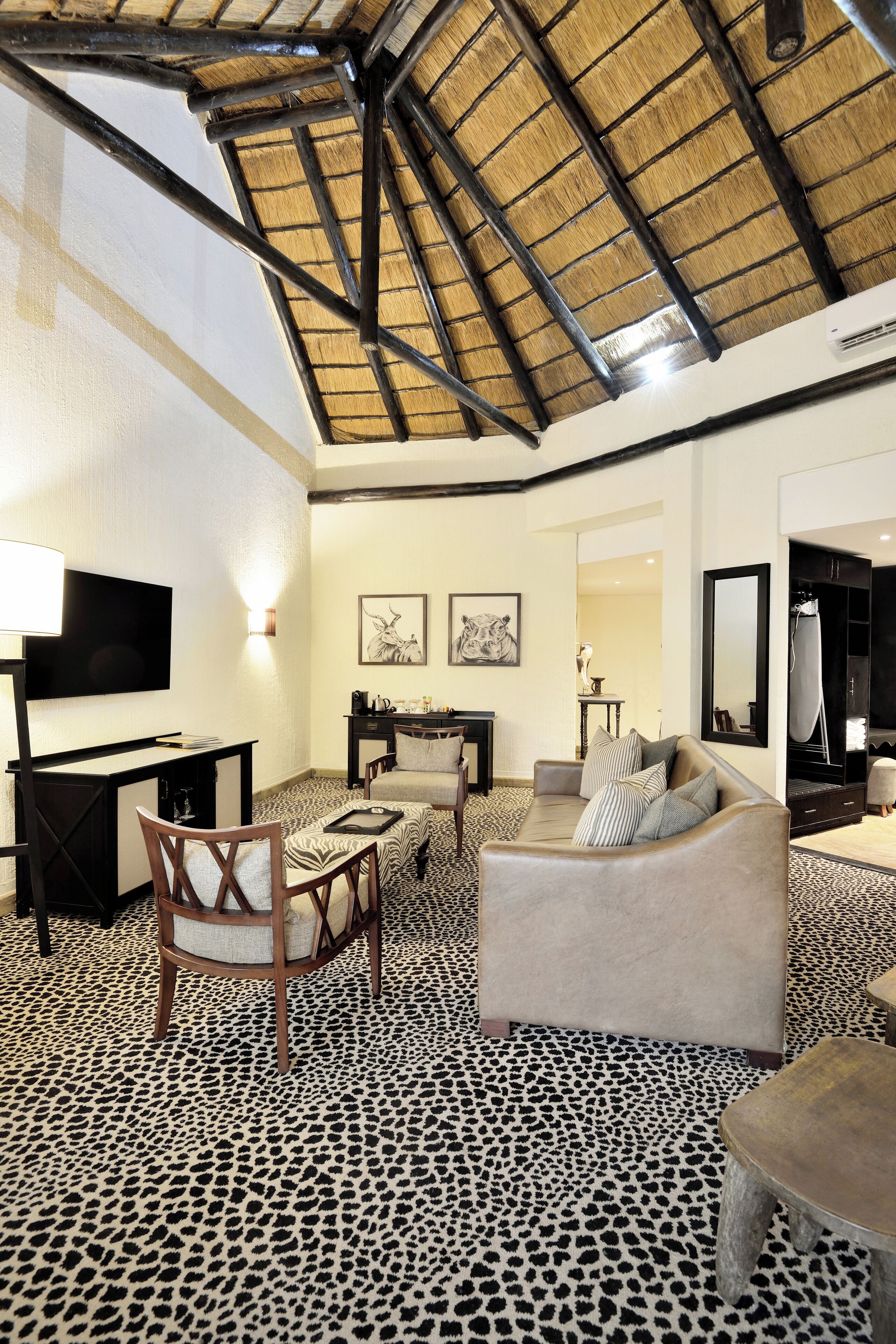 A spacious living area with a high ceiling, a flat-screen TV, a sofa, a chair, and a patterned floor.