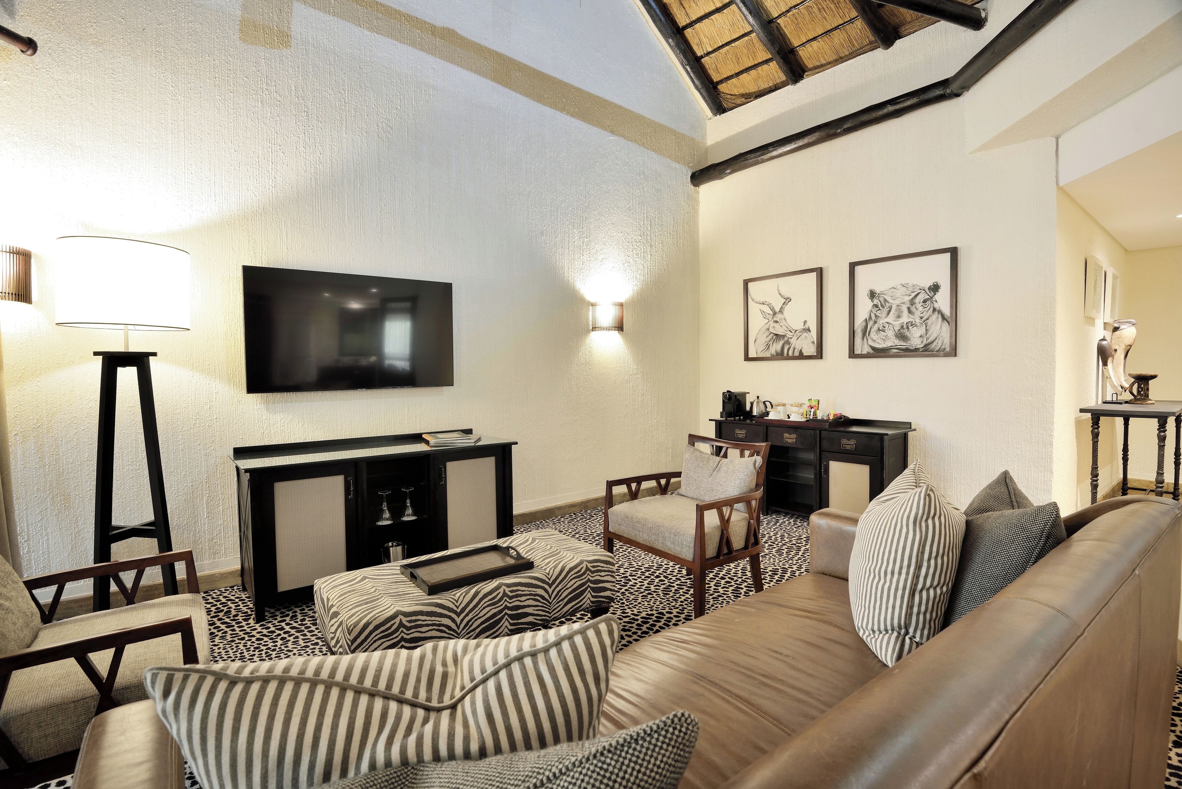 A modern living room with a sofa, armchairs, a coffee table, a TV, and artwork on the wall.