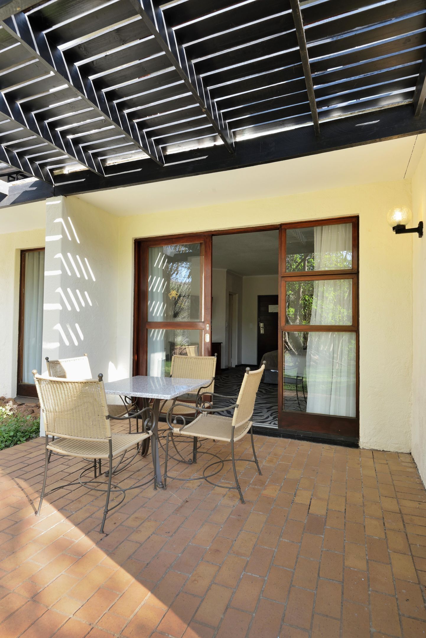 A patio with a table and chairs, a sliding glass door, and a ceiling with a geometric pattern.
