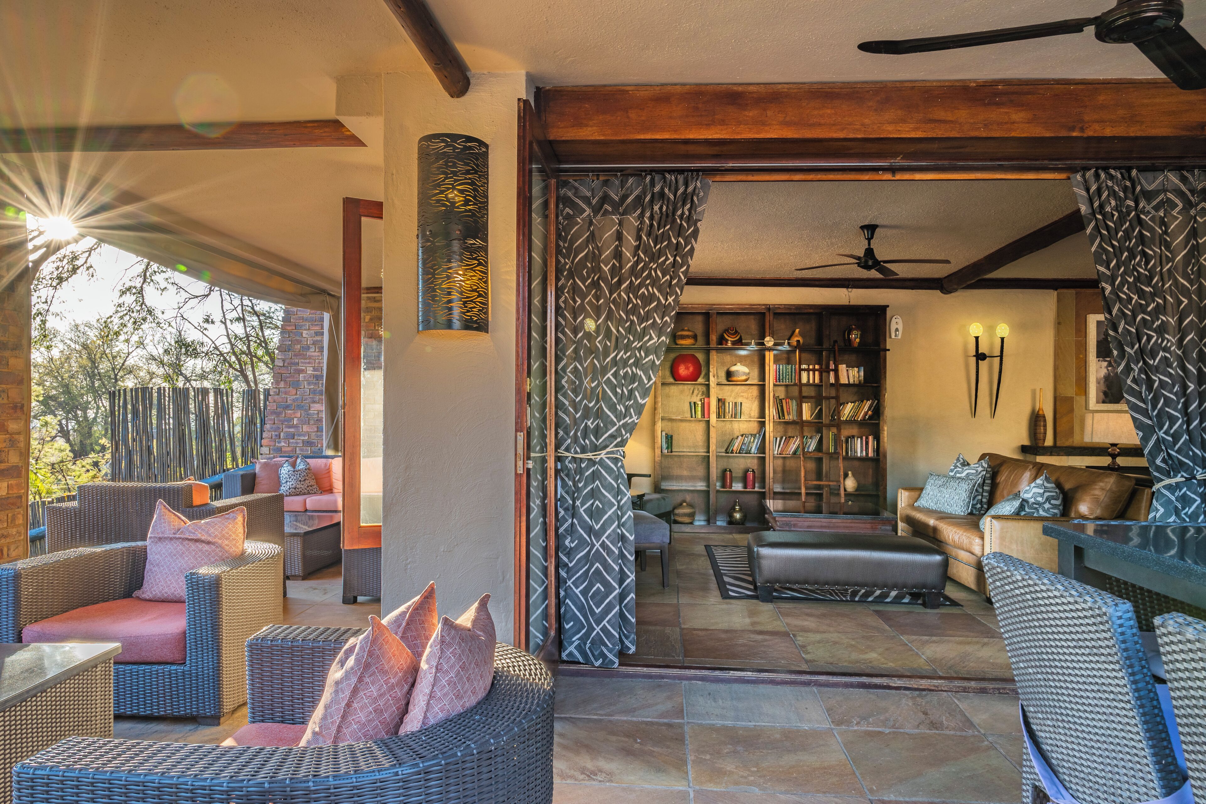 Un amplio salón con mobiliario de mimbre, chimenea y estantería.