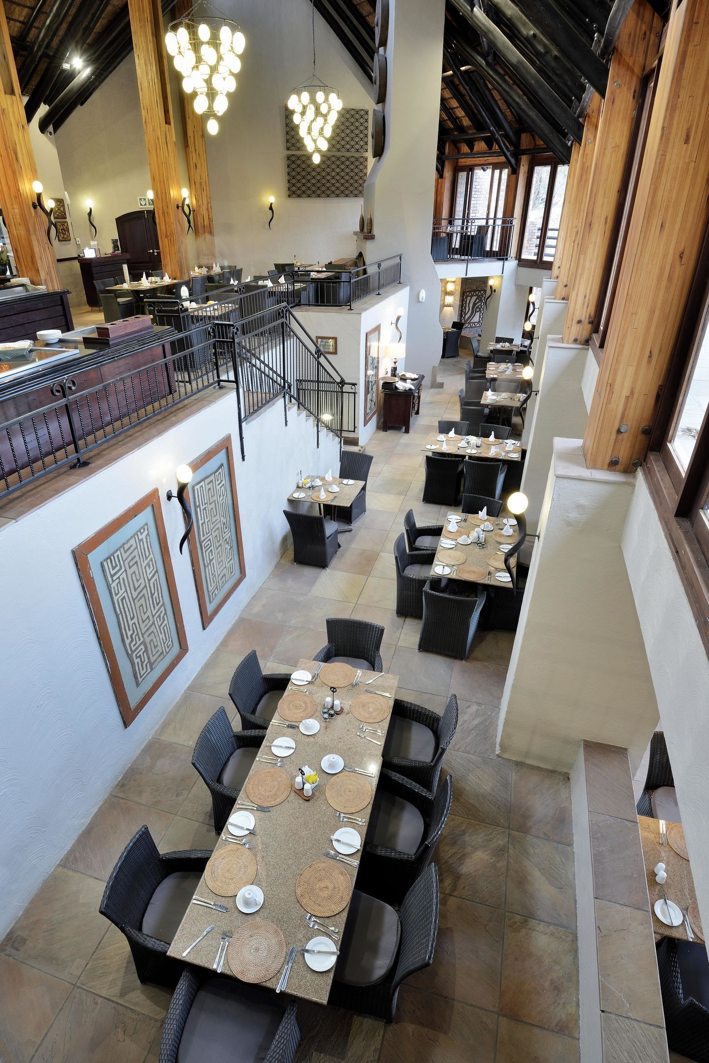 A spacious restaurant with high ceilings, exposed wooden beams, and a variety of seating arrangements including tables and chairs.