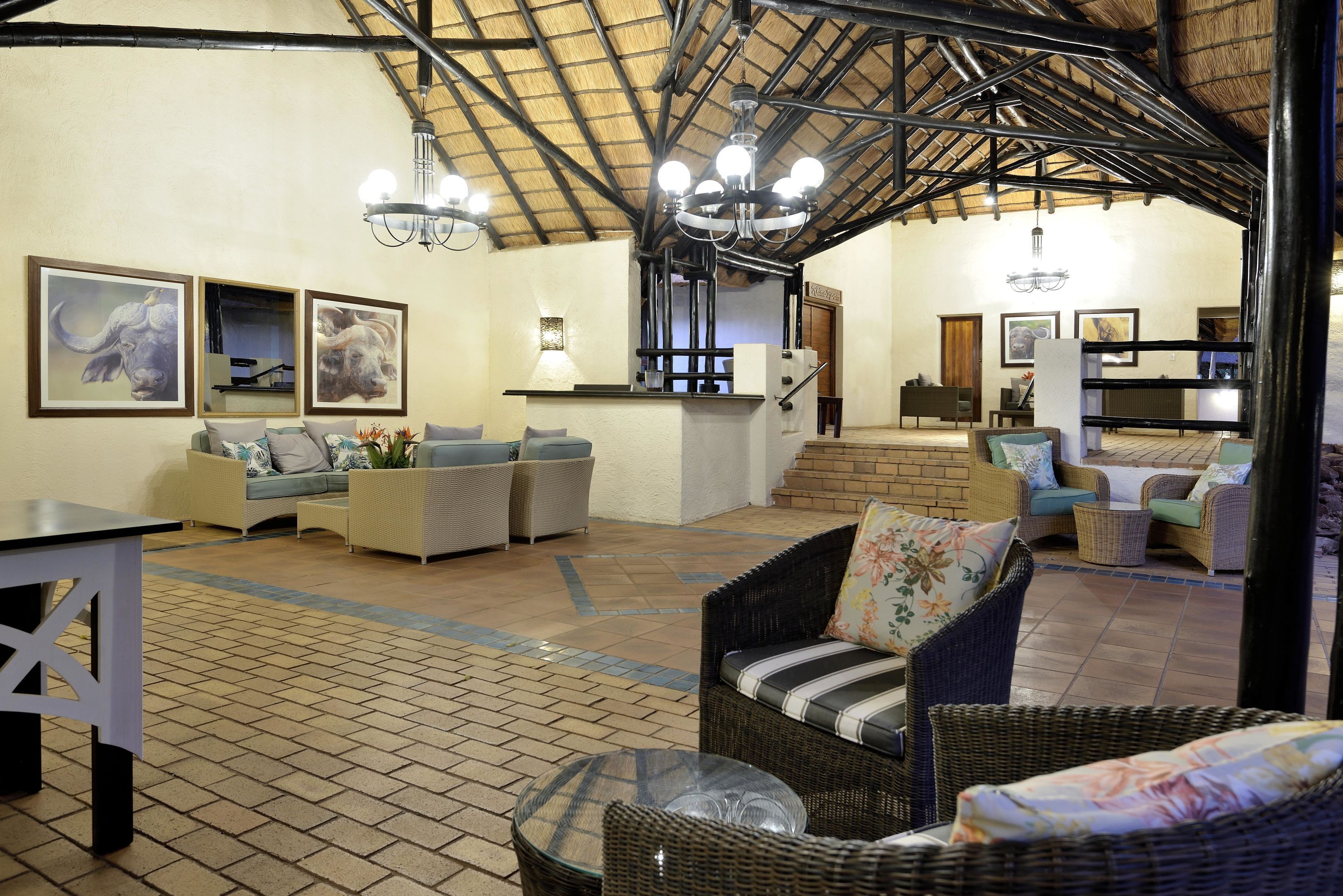 A spacious indoor area with wicker furniture, a tiled floor, and a high ceiling with exposed beams.