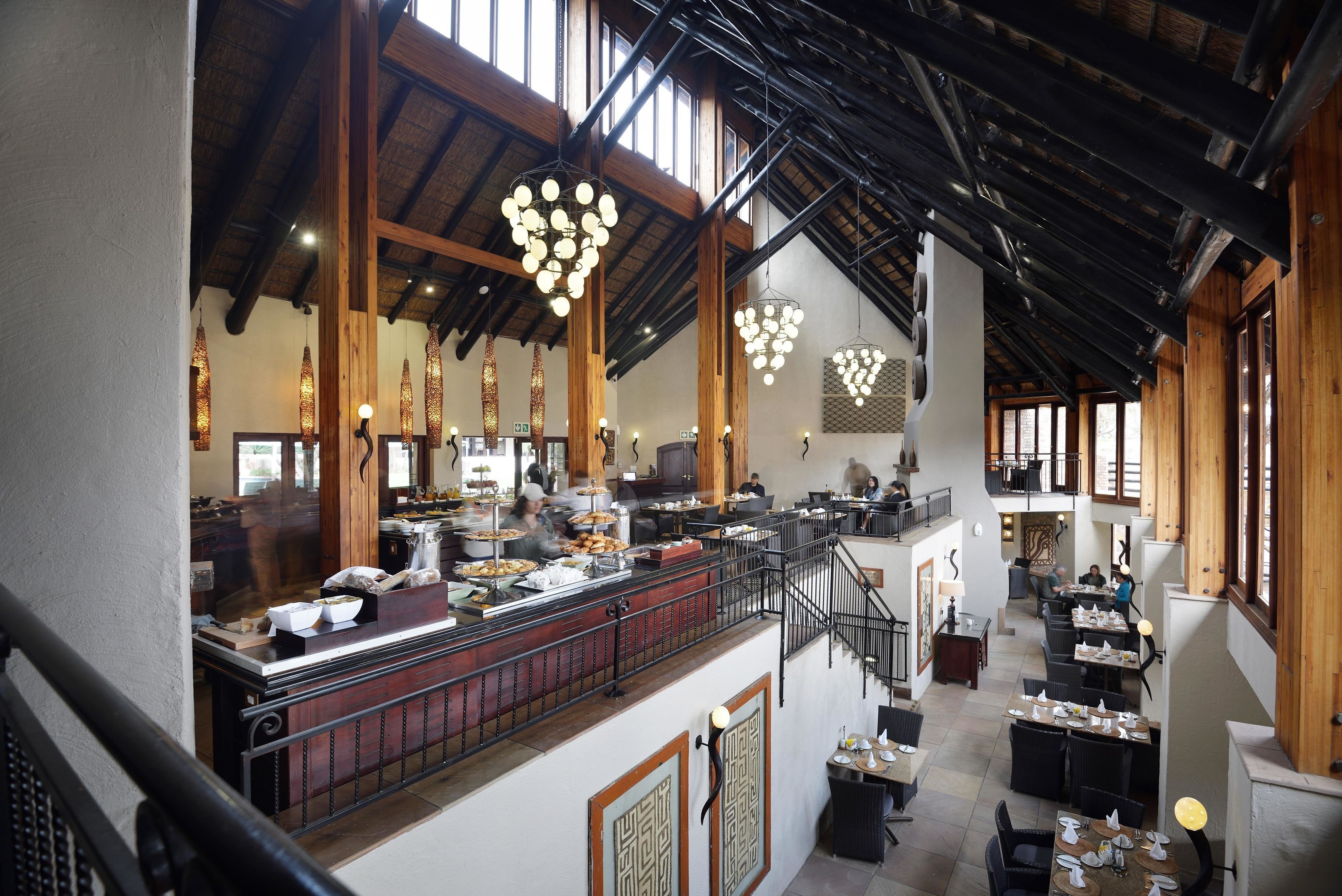 Un restaurant spacieux avec de hauts plafonds, des poutres en bois et des luminaires suspendus.