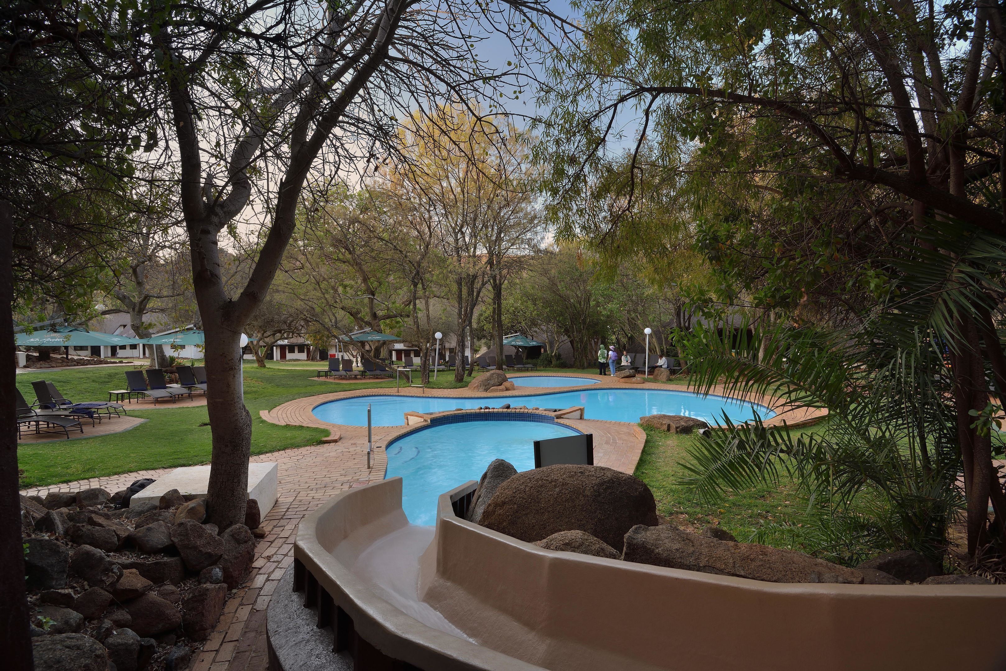A pool area with a slide, lounge chairs, and a landscaped garden.