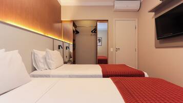 Une chambre d’hôtel avec deux lits, une télévision, une armoire et un miroir.
